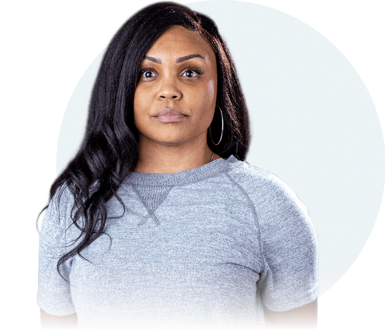 An African-American woman with long brown hair is seen from the waist up. She is looking straight at the camera 