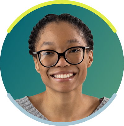 Young African American woman with her braided, she is seen from the neck up. She has dark glasses on and is smiling.