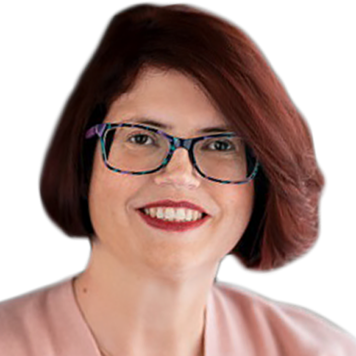 A white woman with short brown hair and patterned glasses is seen from the neck up. She faces the camera with a smile that reveals her teeth