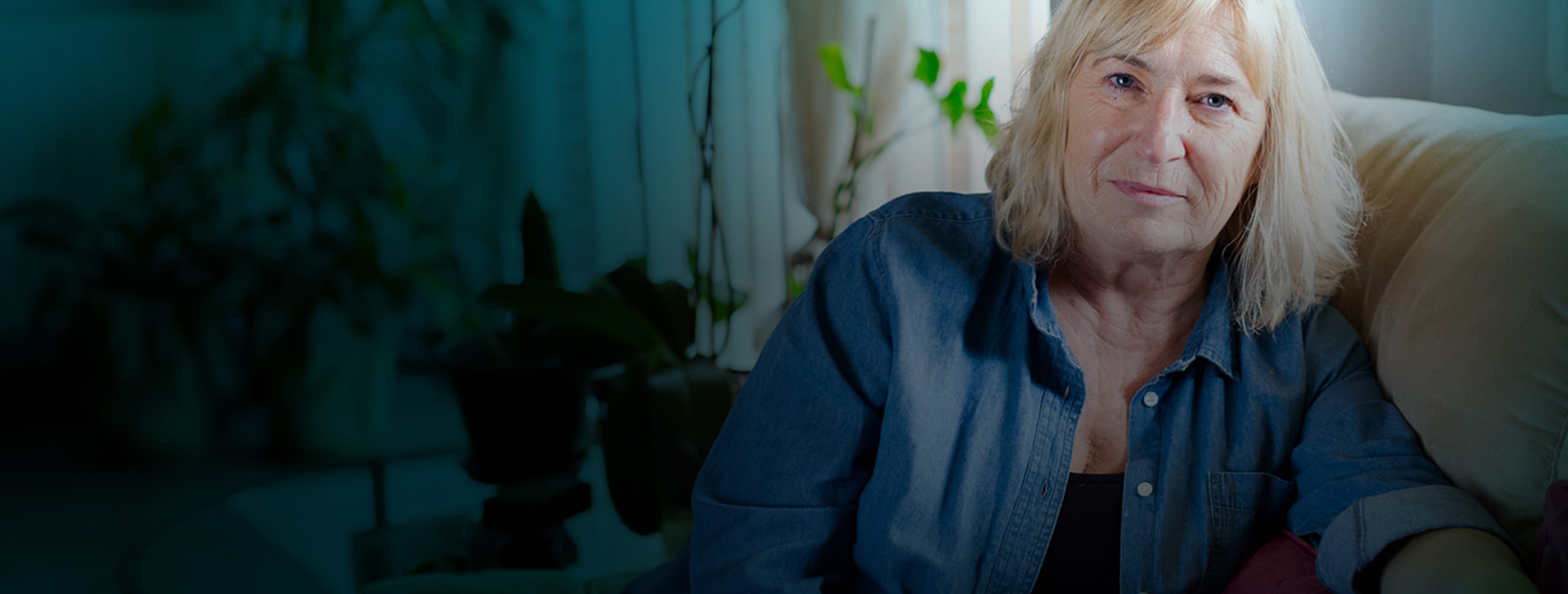 Actor portrayal of a senior woman sitting on her couch.