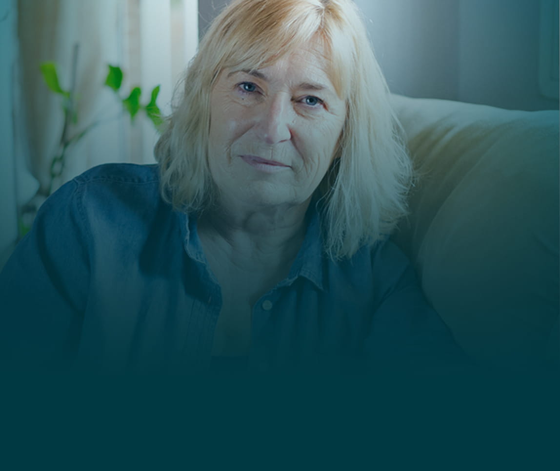 Actor portrayal of a senior woman sitting on her couch.