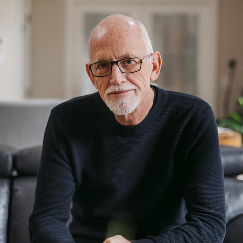 An older white man with white hair, a goatee, and black-rimmed glasses, seen from the chest up.