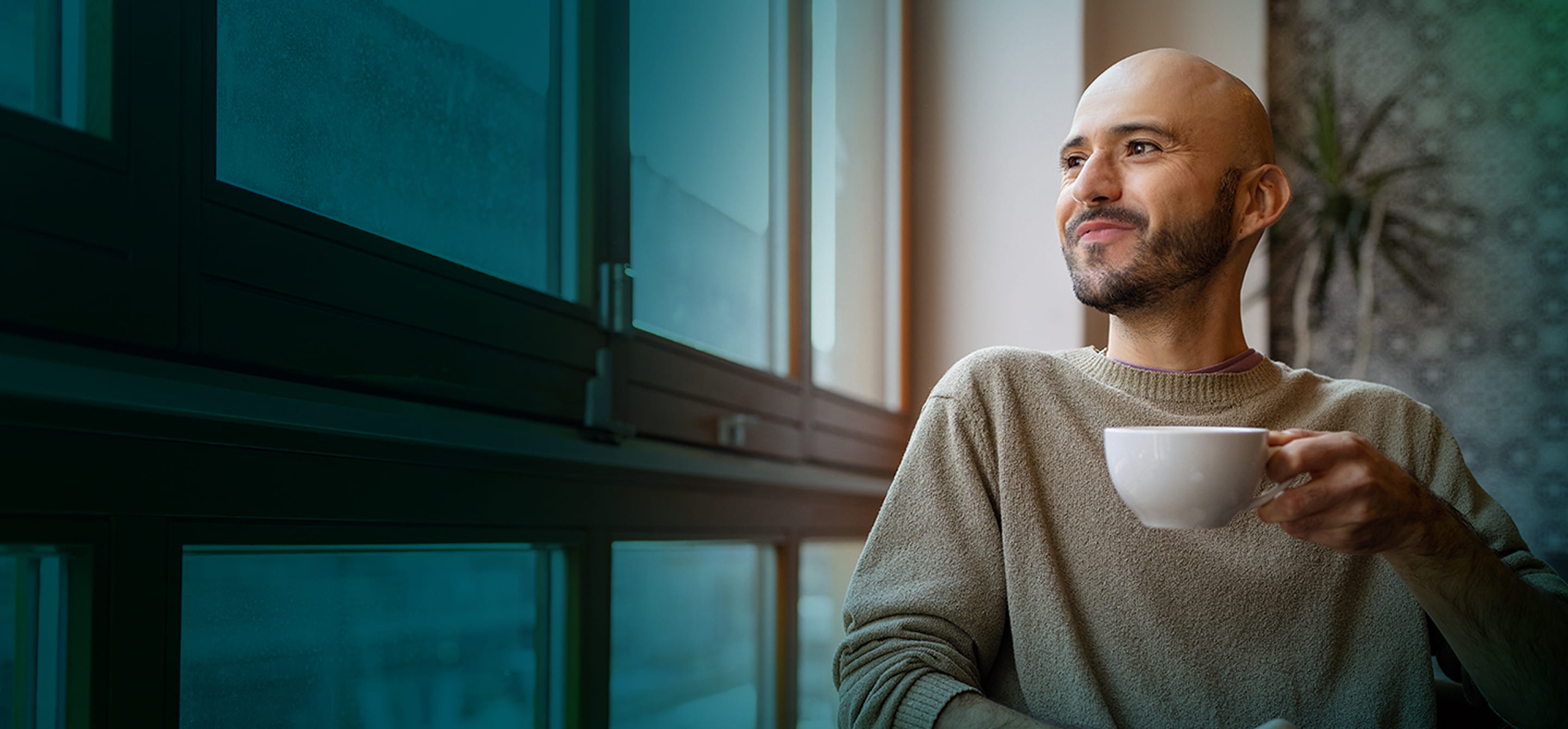 Actor portrayal of a man enjoying a cup of coffee while looking out the window.