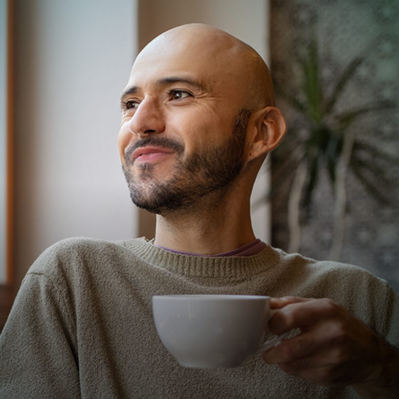Actor portrayal of a a man enjoying a cup of coffee while looking out the window.