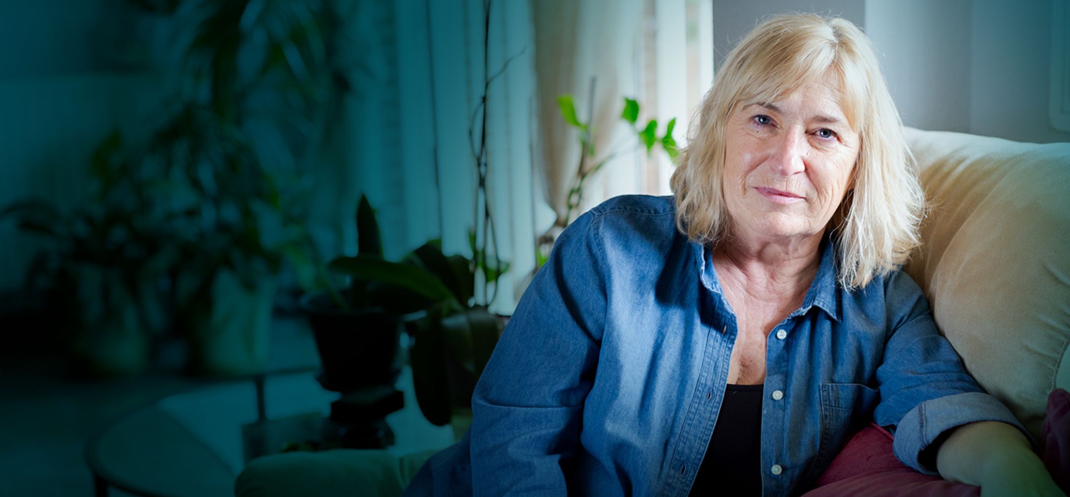 Actor portrayal of a senior woman sitting on her couch.