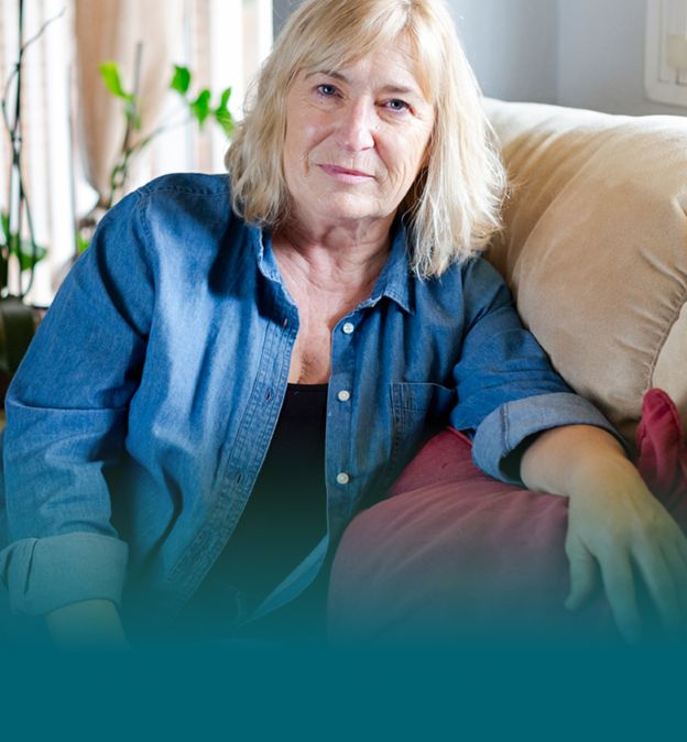 Actor portrayal of a senior woman sitting on her couch.