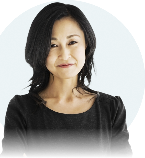 An Asian woman with shoulder-length dark brown hair is seen from the chest up. She is looking straight at the camera and smiling.